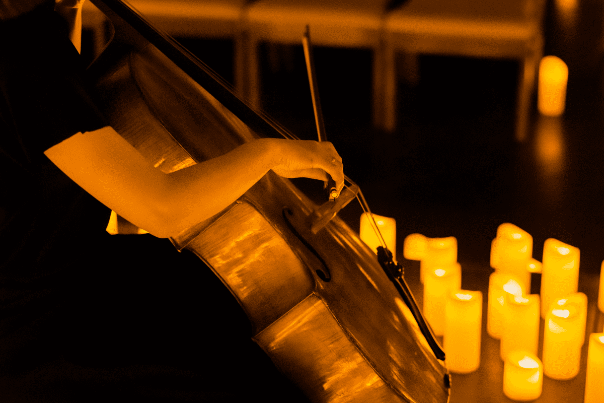 A close up of a cello player surrounded by candles