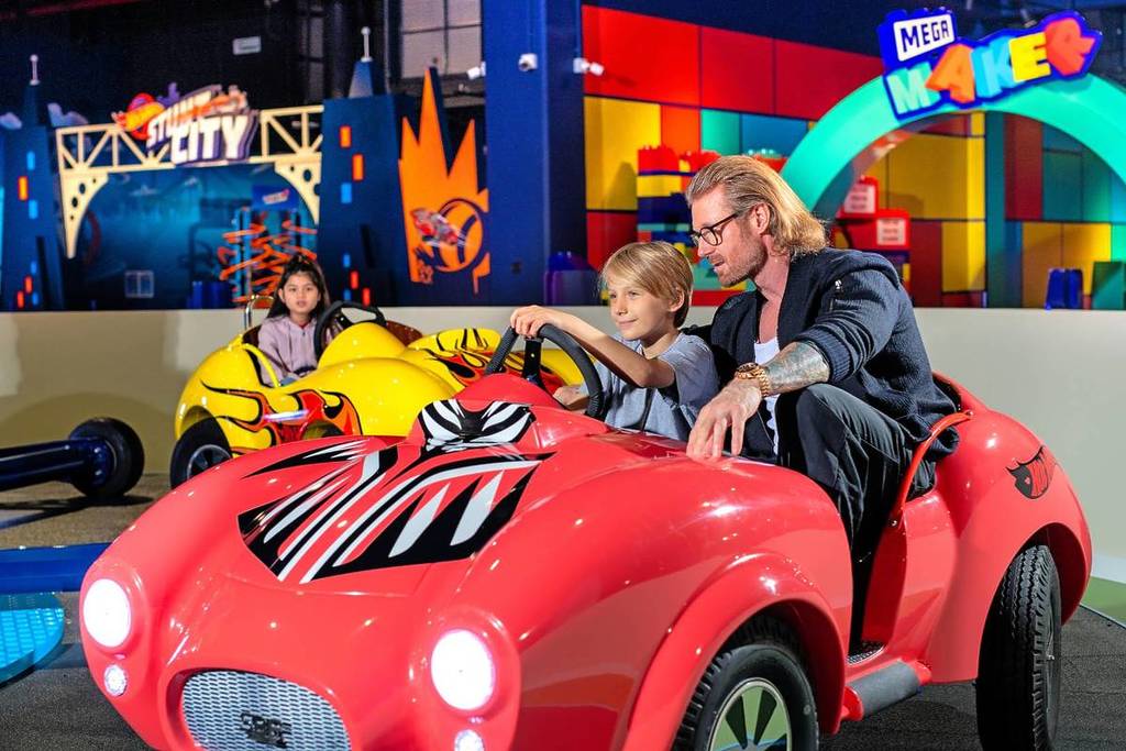 A father and son taking part in a Hot Wheels ride for family fun during the school holidays