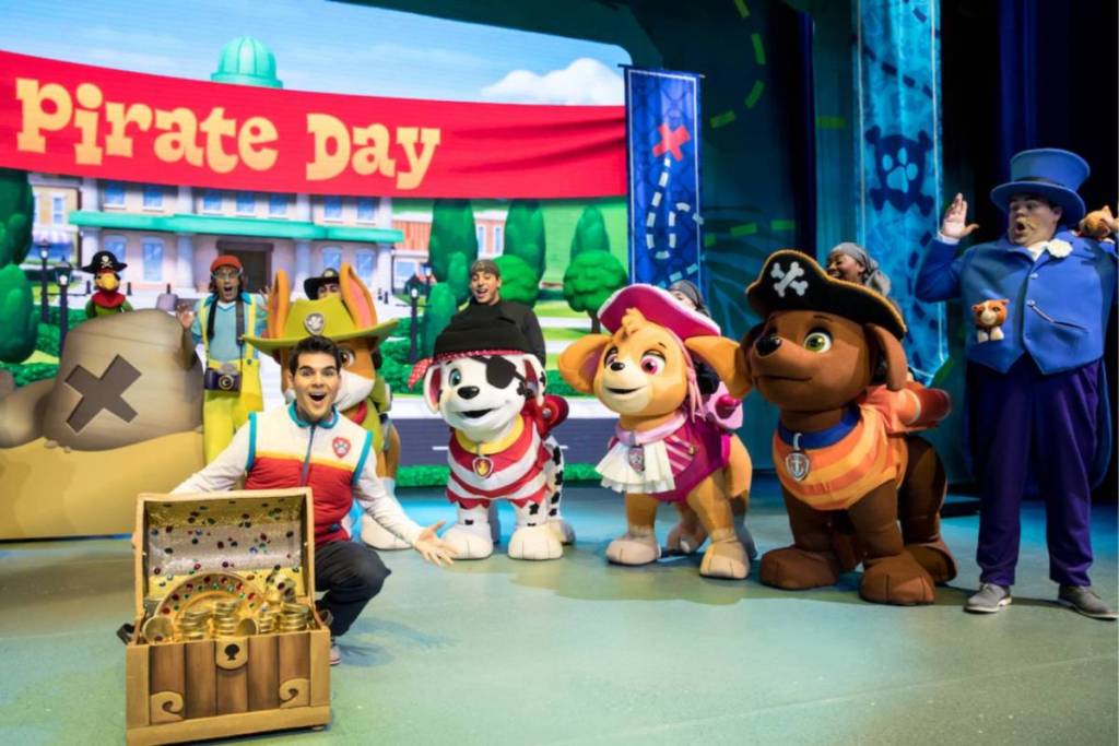 The PAW Patrol cast stood in front of a pirate banner, smiling over a treasure chest