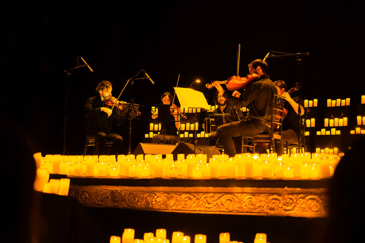 Un cuarteto de cuerda toca sobre un escenario cubierto de velas durante un concierto Candlelight en Buenos Aires.