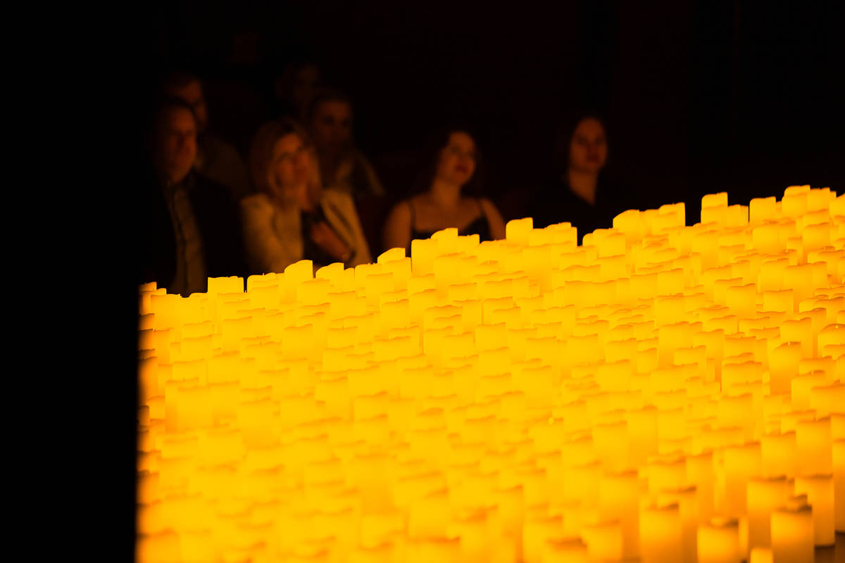 Miles de velas colocadas en un escenario y público de fondo