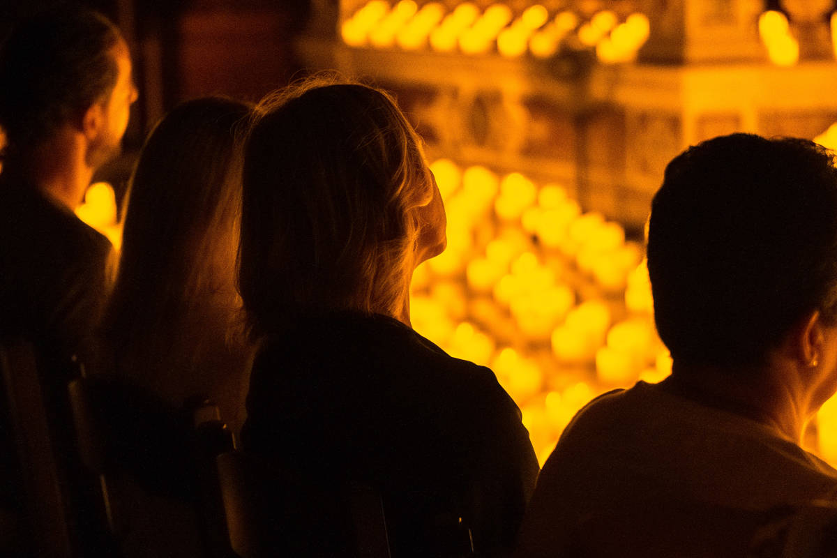 Una espectadora mira atenta hacia el escenario cubierto de velas durante un concierto Candlelight.
