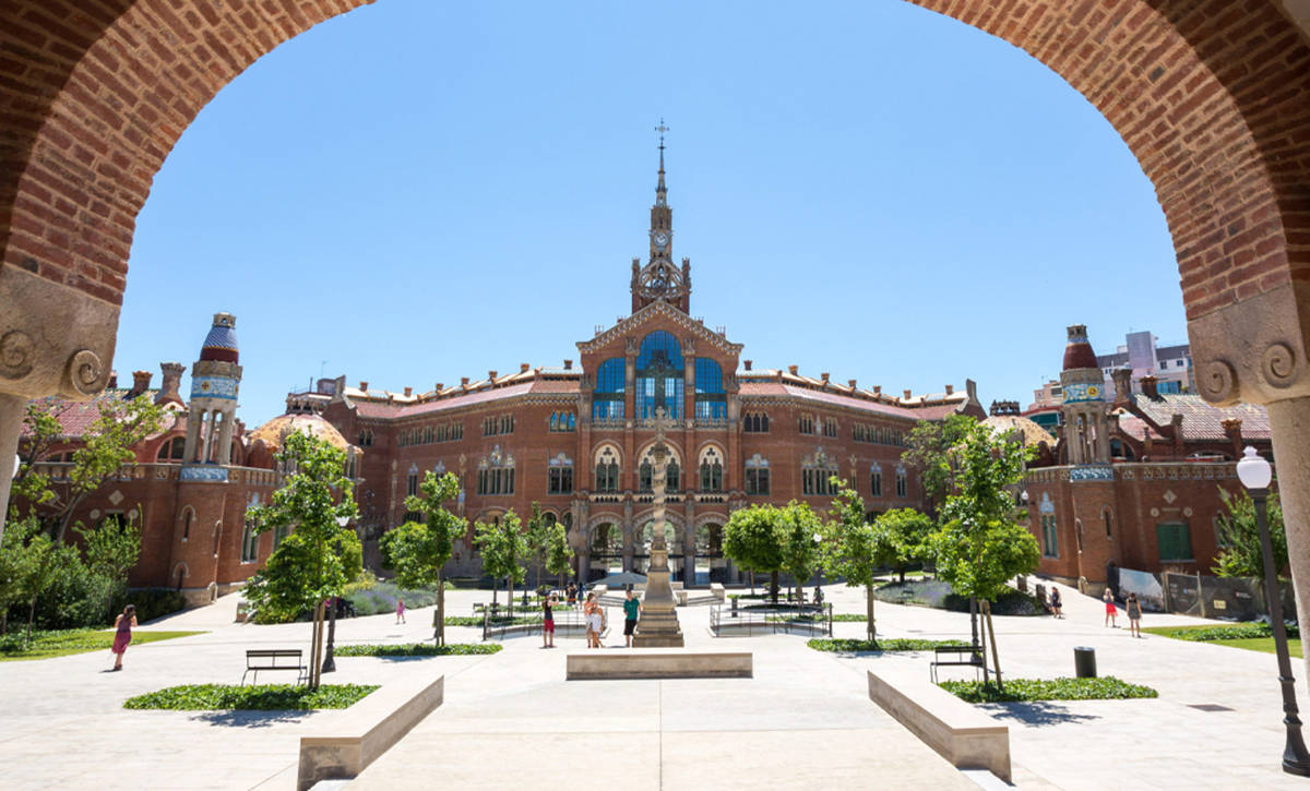 Fachada principal del Recinto Modernista de Sant Pau en Barcelona, vista desde el arco de entrada en un día soleado.