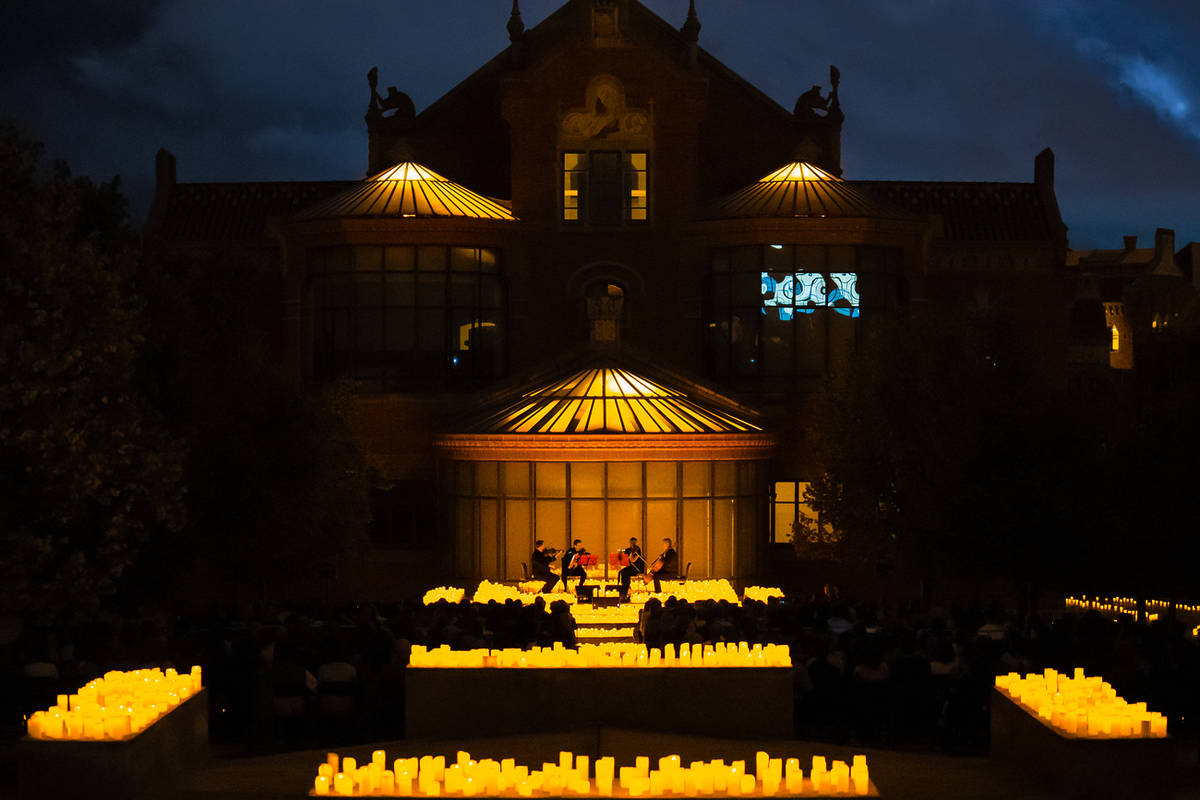 Concierto Candlelight en el Recinto Modernista de Sant Pau en Barcelona, con cuarteto de cuerda rodeado de miles de velas encendidas al aire libre de noche.