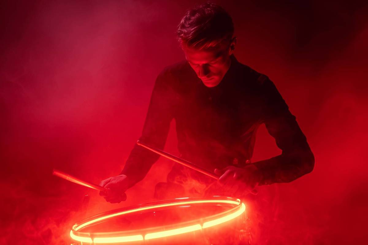 Un músico profesional toca un tambor iluminaod con luces LED en The Colorbeat Drums.