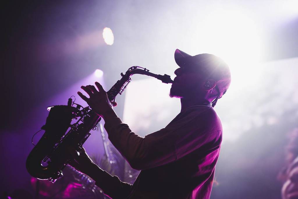 Músico a tocar saxofone num palco com luzes roxas durante um concerto de jazz em Barcelona.