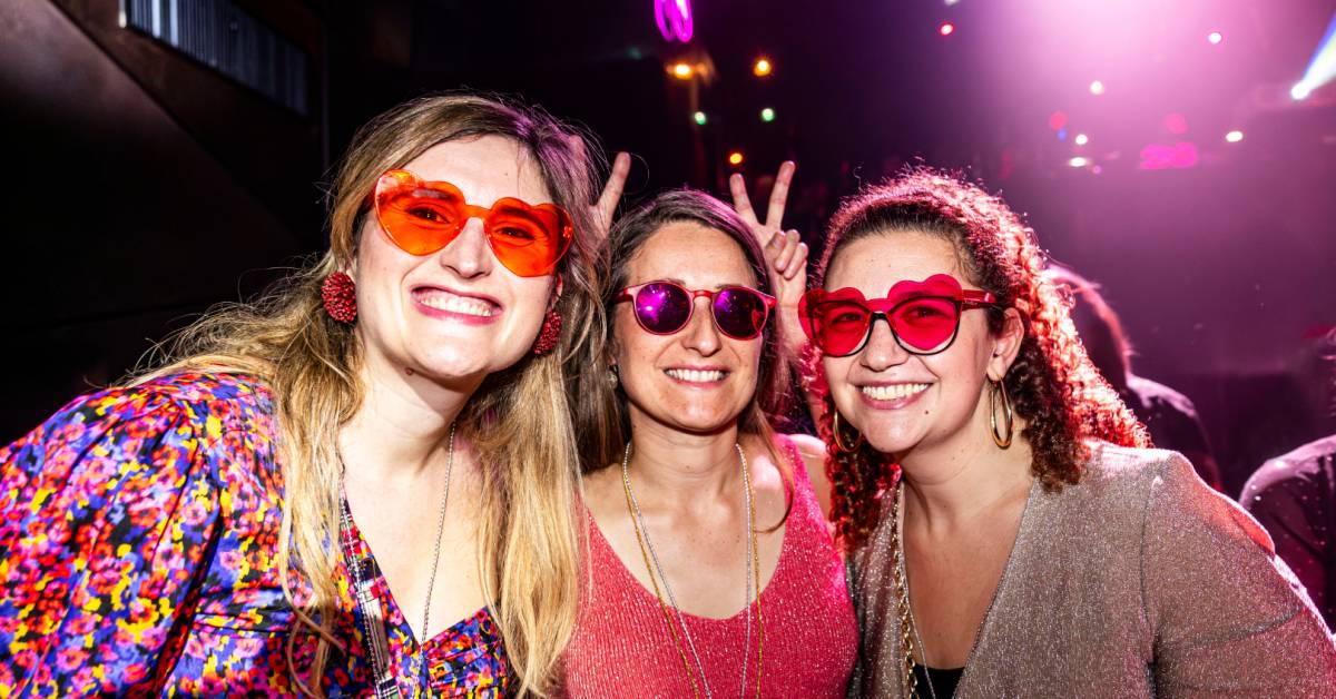Tres chicas vestidas disco sonríen a cámara durante la fiesta de Gimme Gimme Disco.