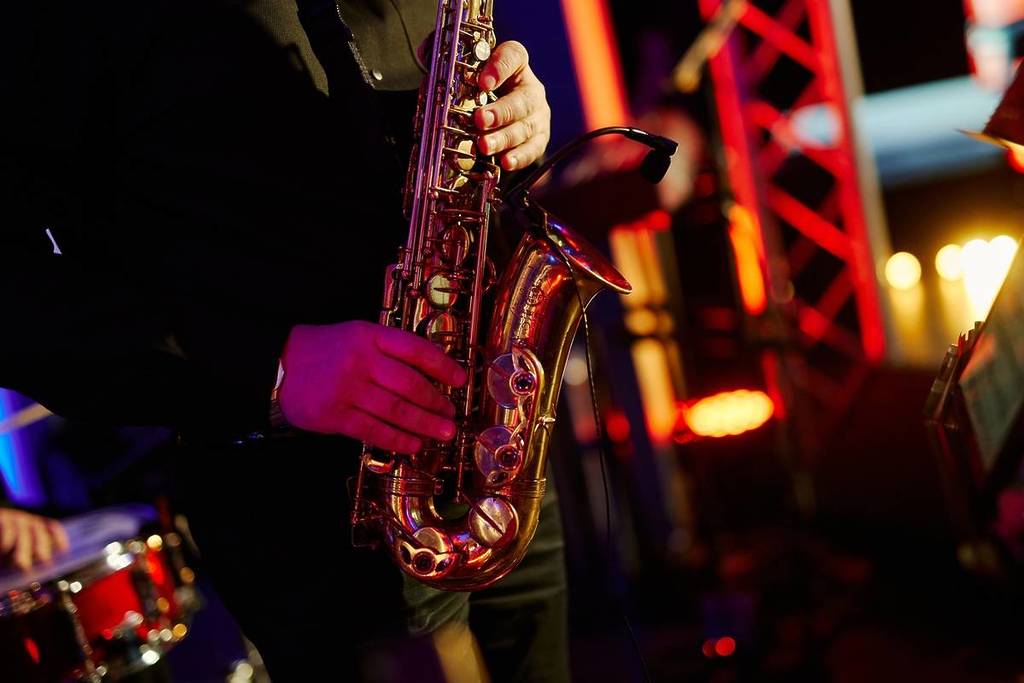 Manos sujetando un saxofón durante un concierto de jazz