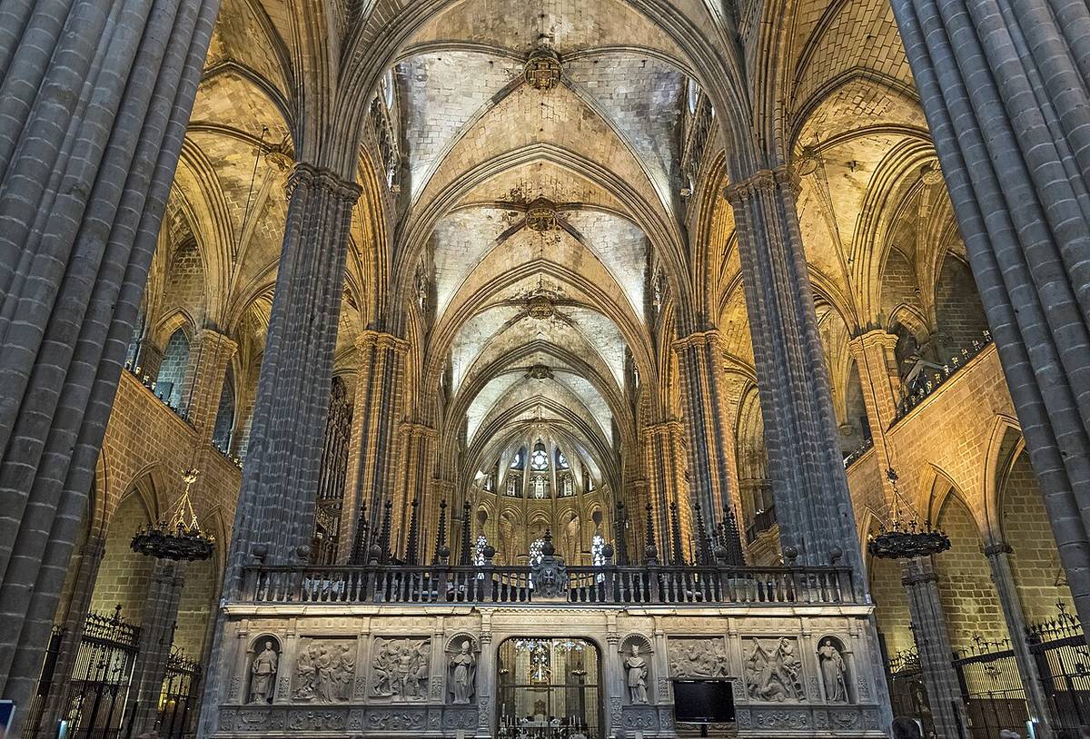Interior gótico de la Catedral de Barcelona con bóvedas altas, columnas monumentales y vista del coro central iluminado