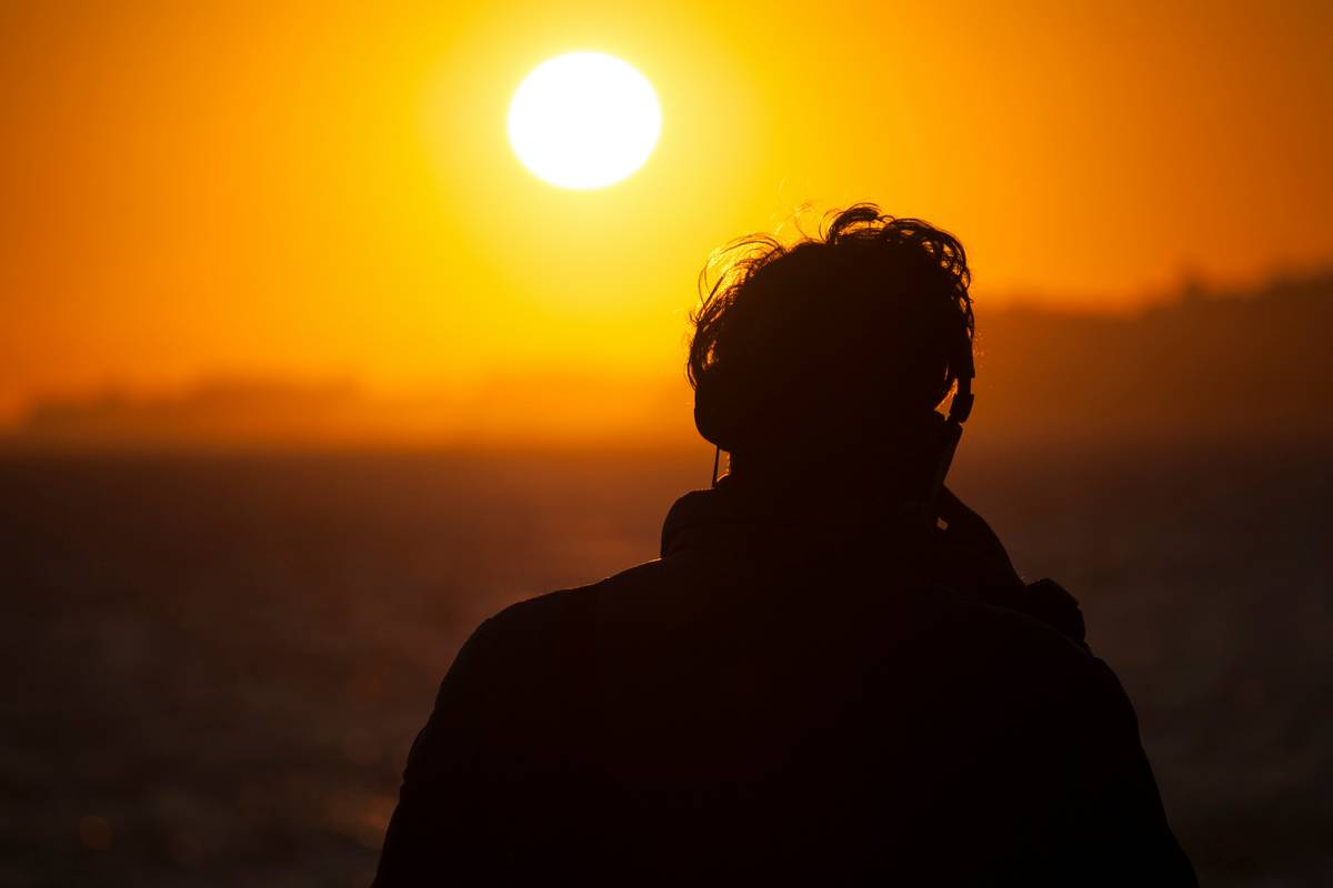 Persona escuchando música con auriculares al atardecer, una imagen que evoca calma y refugio emocional durante los días de invierno.