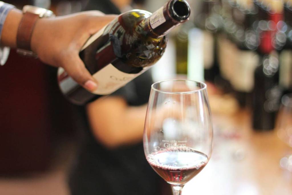 Plano de una mando cogiendo una botella de vino después de servir en una copa.