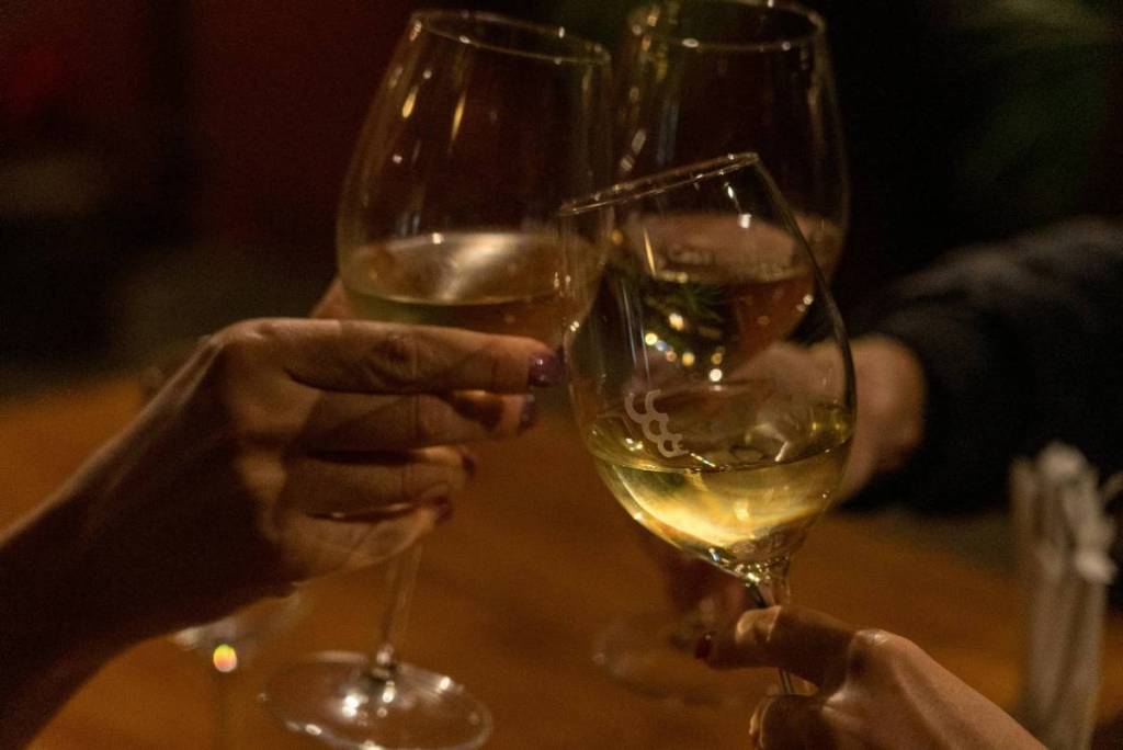 Primer plano de tres copas con vino blanco brindando.