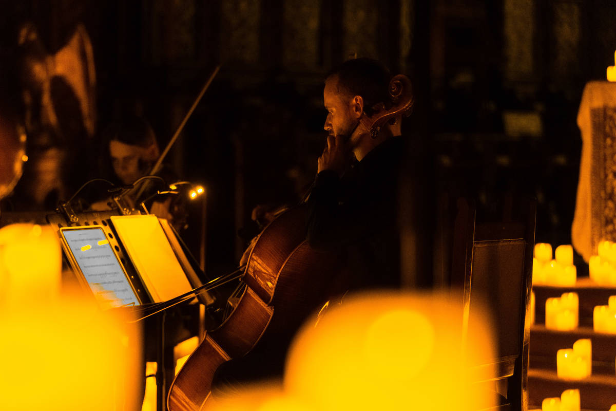 Plano medio de dos músicos tocando sobre un escenario cubierto de velas durante un concierto Candlelight.