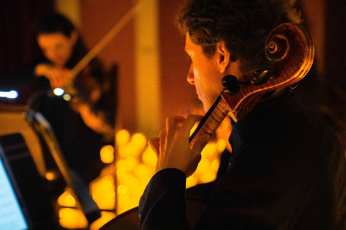 Primer plano de un violonchelista sobre un escenario cubierto de velas durante un concierto Candlelight.