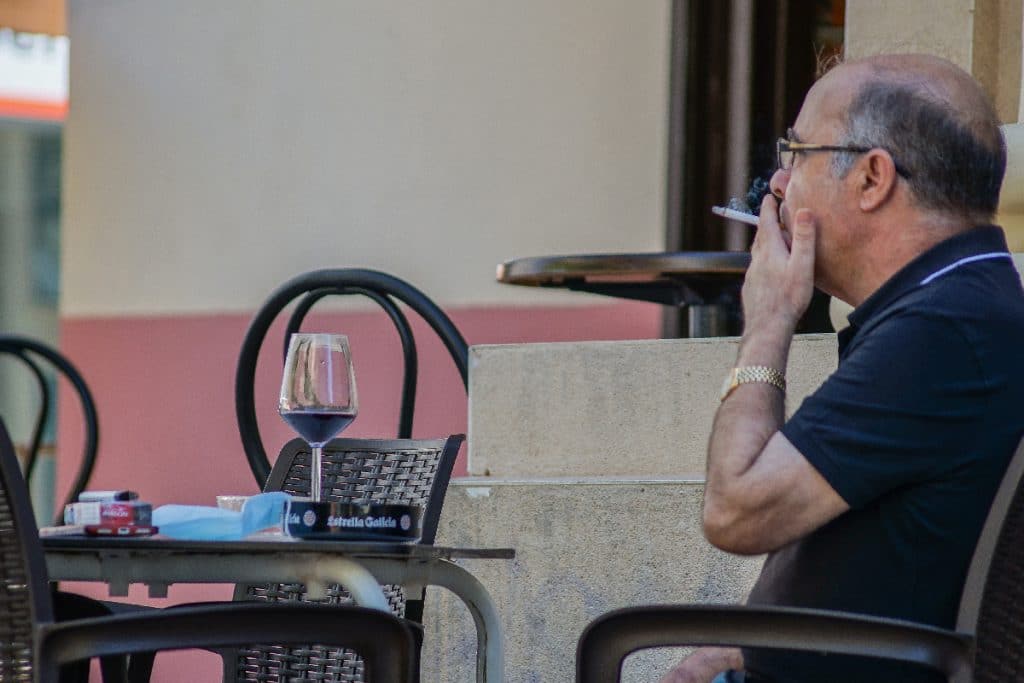 Hombre fumando en la terraza de un bar.