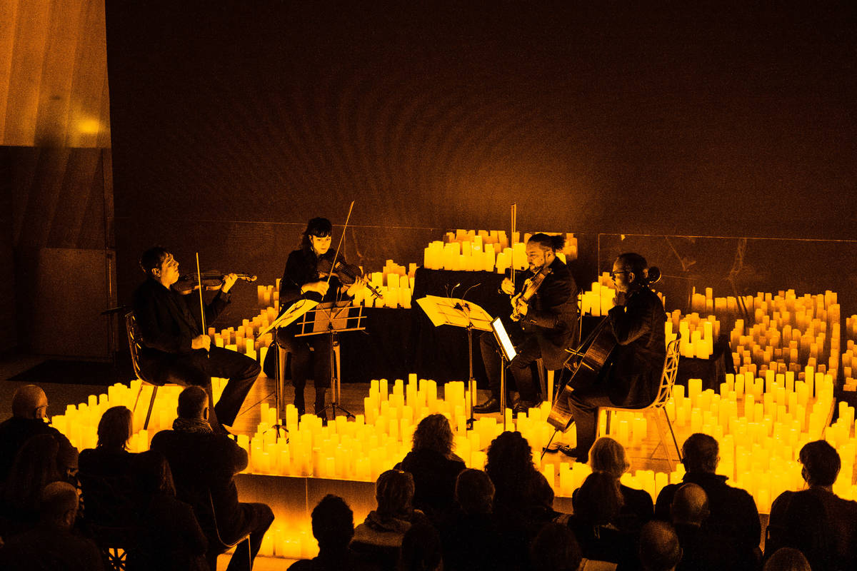 Un cuarteto de cuerda toca sobre un escenario cubierto de velas durante un concierto Candlelight.