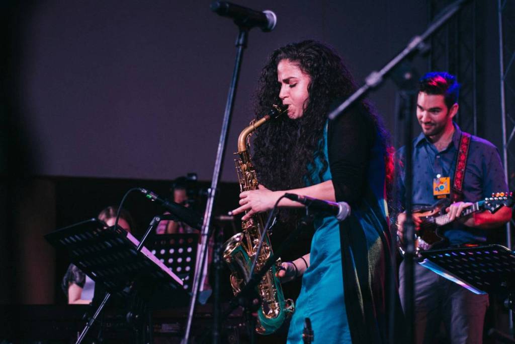 Photo d'une femme jouant du saxophone sur scène avec son groupe de musique