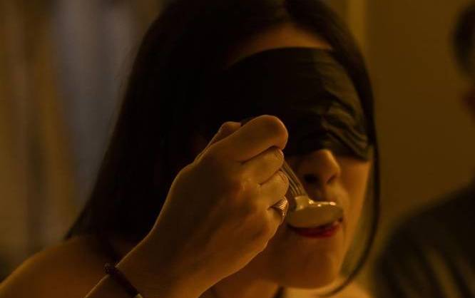 A blindfolded woman enjoying a meal at Dining in the Dark