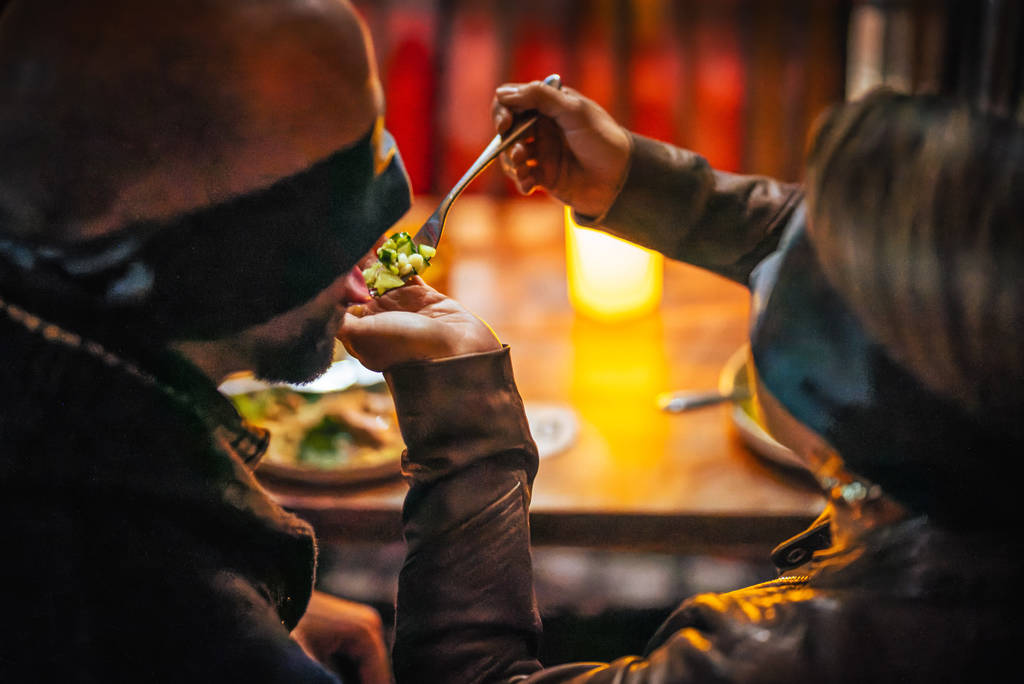 A blindfolded couple feeding each other at Dining in the Dark
