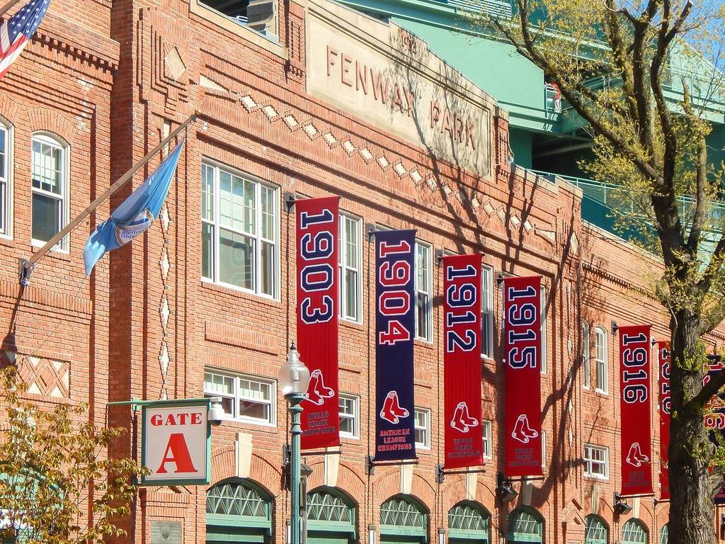 The façade of Fenway Park decorated with various flags of the Red Sox team throughout the years for the Boston bucket list.