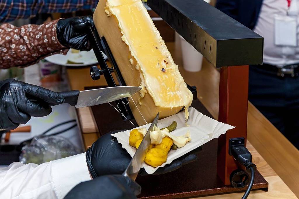 raclette cheese half wheel melting over potatoes