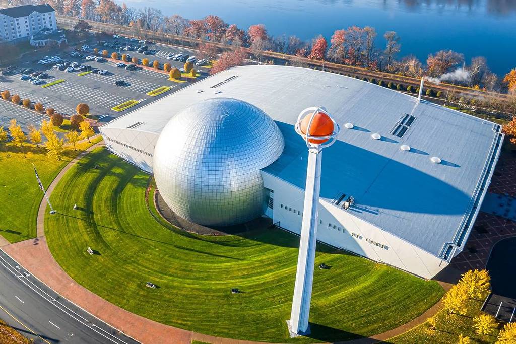 High-angle drone shot of the Naismith Memorial Basketball Hall of Fame with its iconic silver dome and giant basketball sculpture, perfect for sports tourism and architecture themes