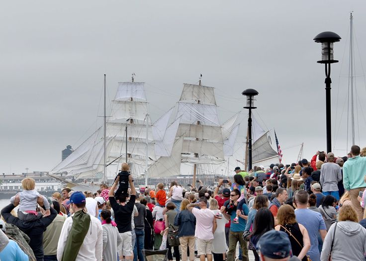 spectators overlooking tall ships