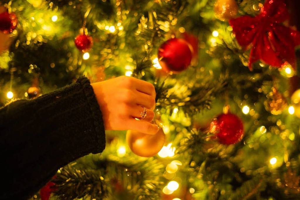 Arbre de Noël en train d'être décoré avec des boules colorées et des guirlandes lumineuses