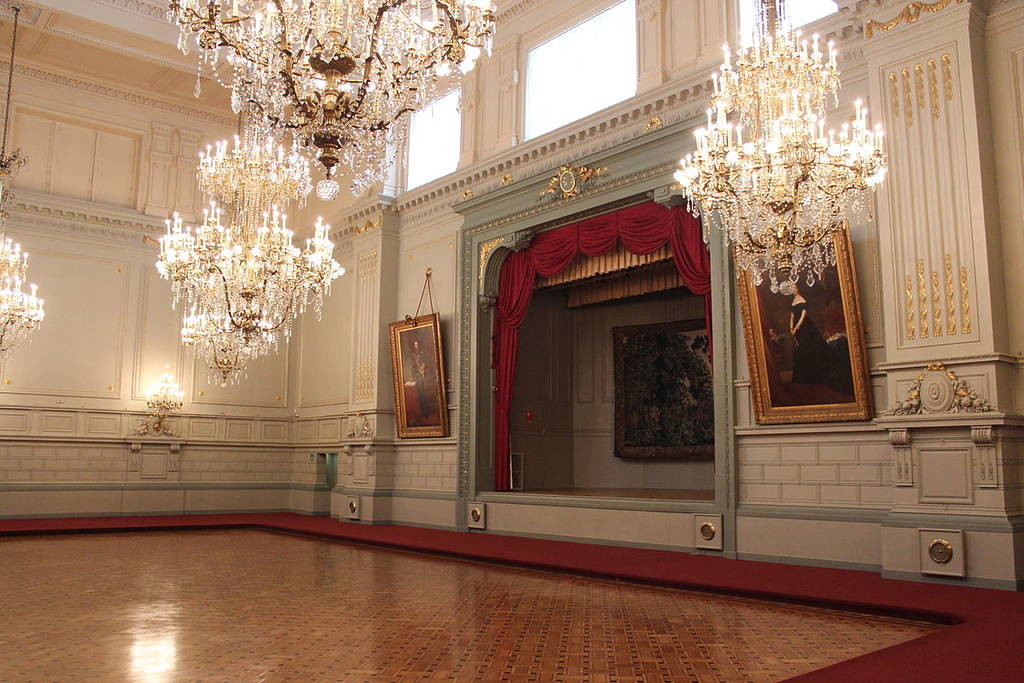 Photo of the interior of the Concert Noble in Brussels, with paintings, stage, curtain and crystal chandeliers