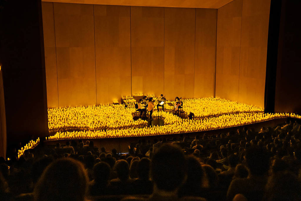 A string quartet plays on a candlelit stage during a Candlelight concert.