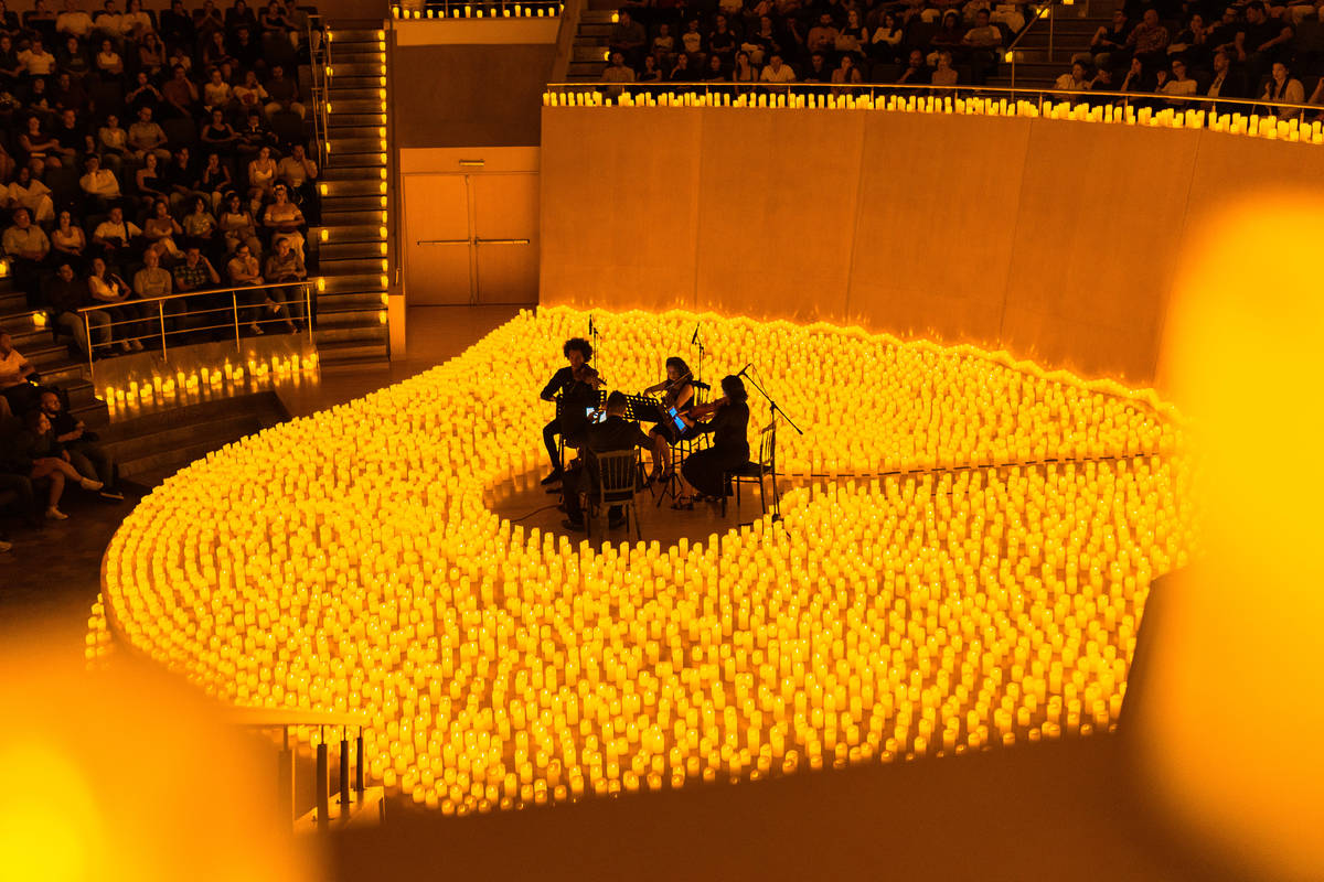 Un cuarteto de cuerda toca sobre un escenario cubierto de velas durante un concierto Candlelight.