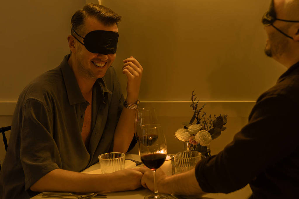 Pareja de hombres disfrutando de una cena con los ojos vendados