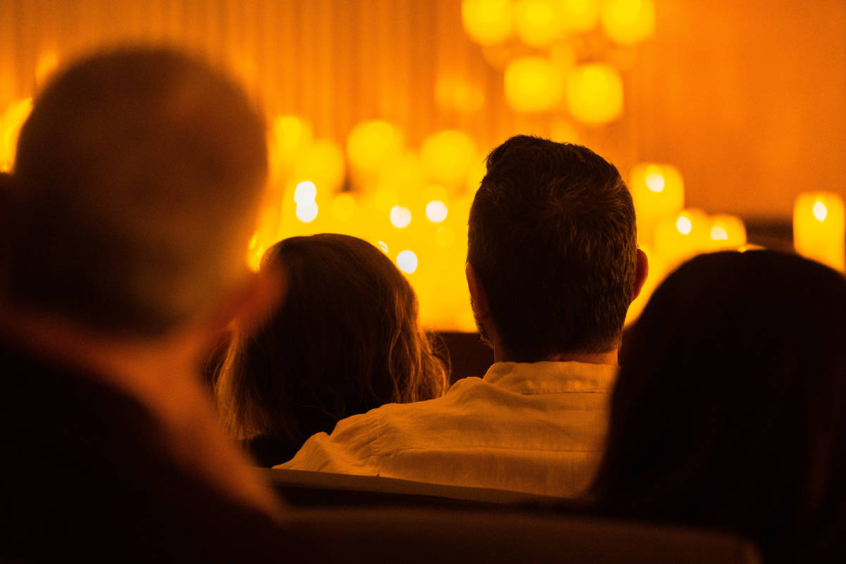 Una pareja mira hacia un escenario cubierto de cálidas velas durante un concierto Candlelight.
