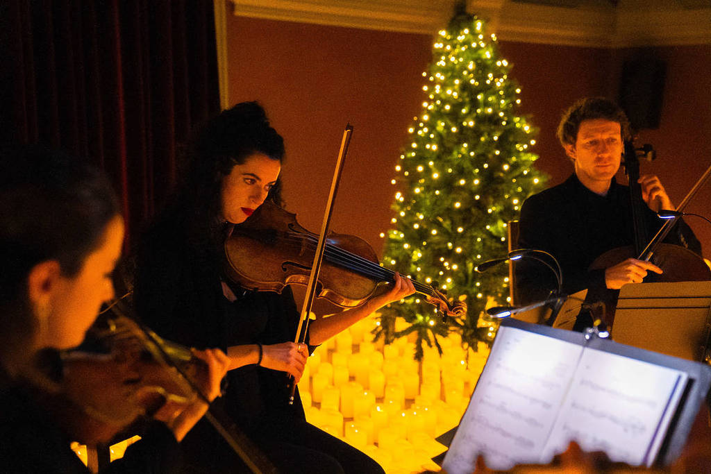 A string quartet plays on a candlelit stage during a Candlelight concert.