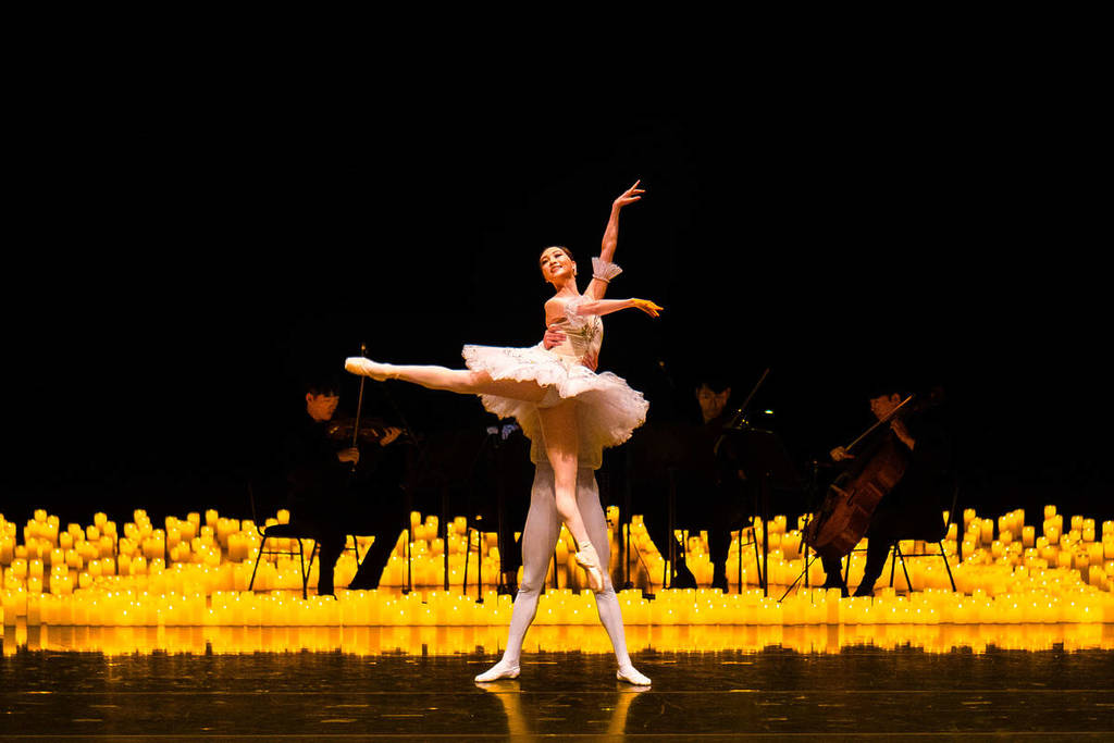 Dos bailarines bailan sobre un escenario cubierto de velas en el que hay un cuarteto de cuerda durante Candlelight Ballet.