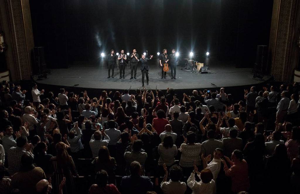 Plano general del final del concierto de Miguel Poveda en México. él da las gracias al público, que aplaude de pie.