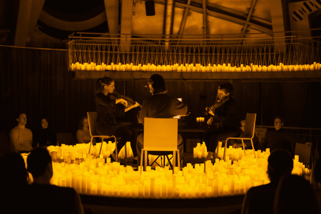 A string quartet performing on stage by candlelight