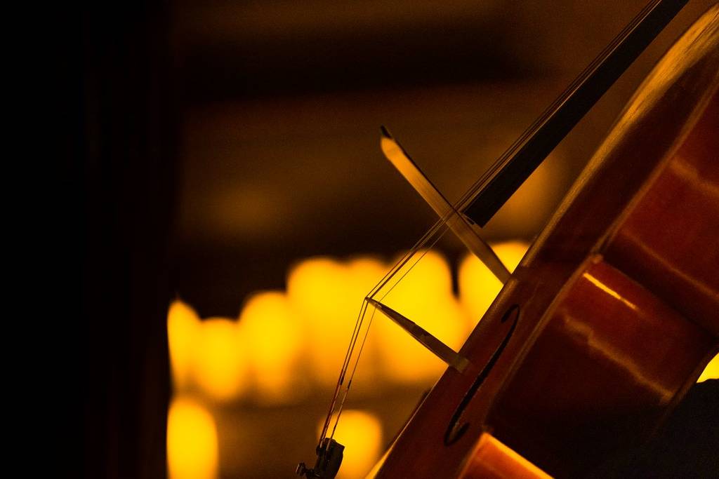 A close-up picture of a cello by candlelight.