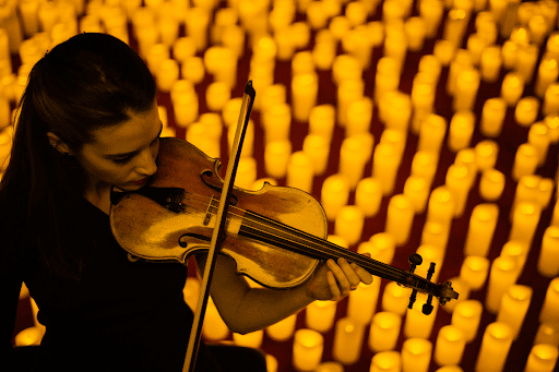 Close up of a musician playing the violin with a backdrop of candles