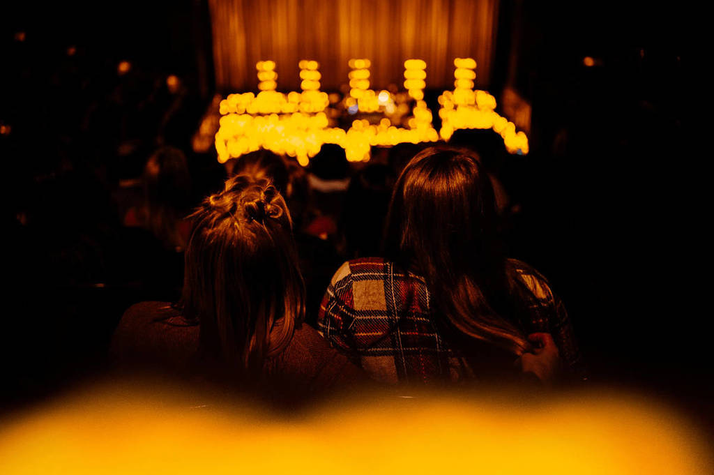 The back of two people's heads looking out across a sea of candles.