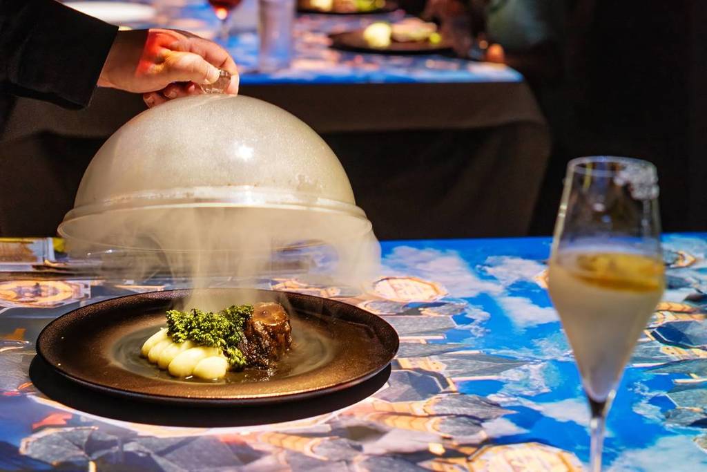 One of the dishes of a three course meal and a glass of wine