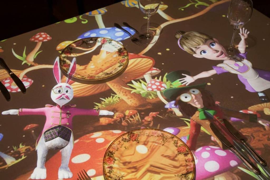 The rabbit mad hatter and Alice projected on the table at Sensory Feast dinner and show