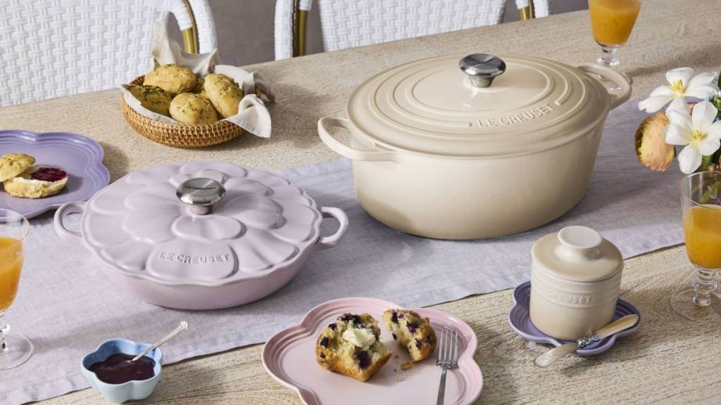 a selection of le creuset cast iron products on a dining table including the petal shape shallow casserole dish