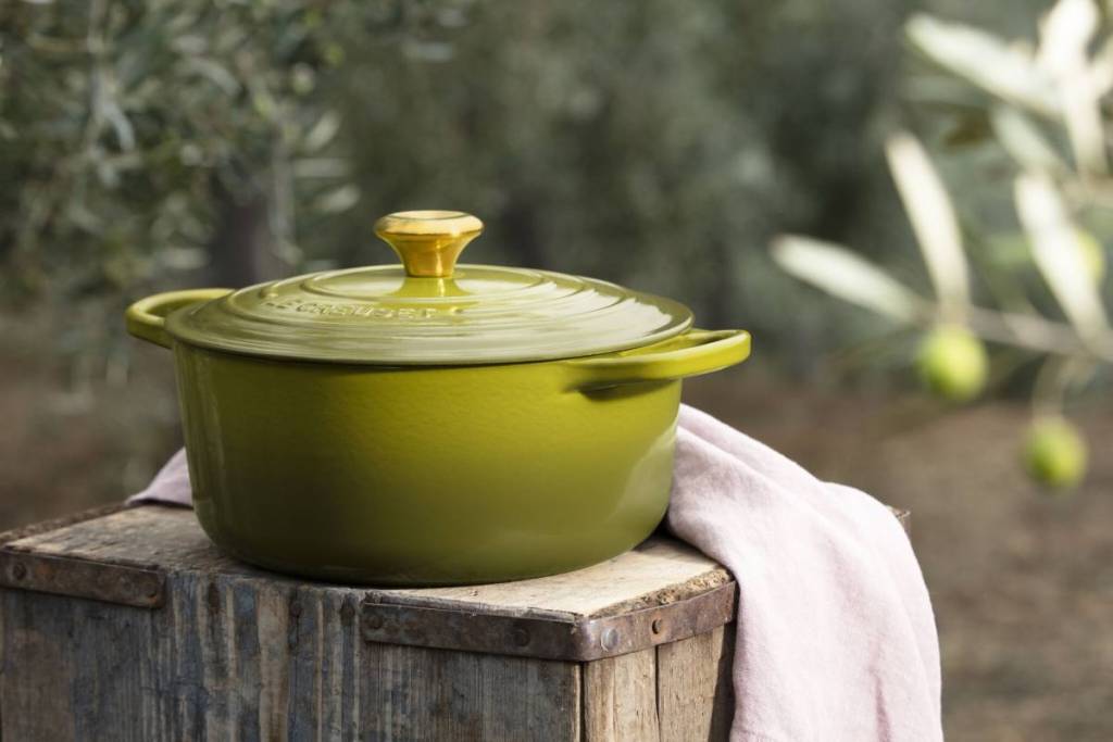 an olive green le creuset casserole pot on wooden box in an olive grove