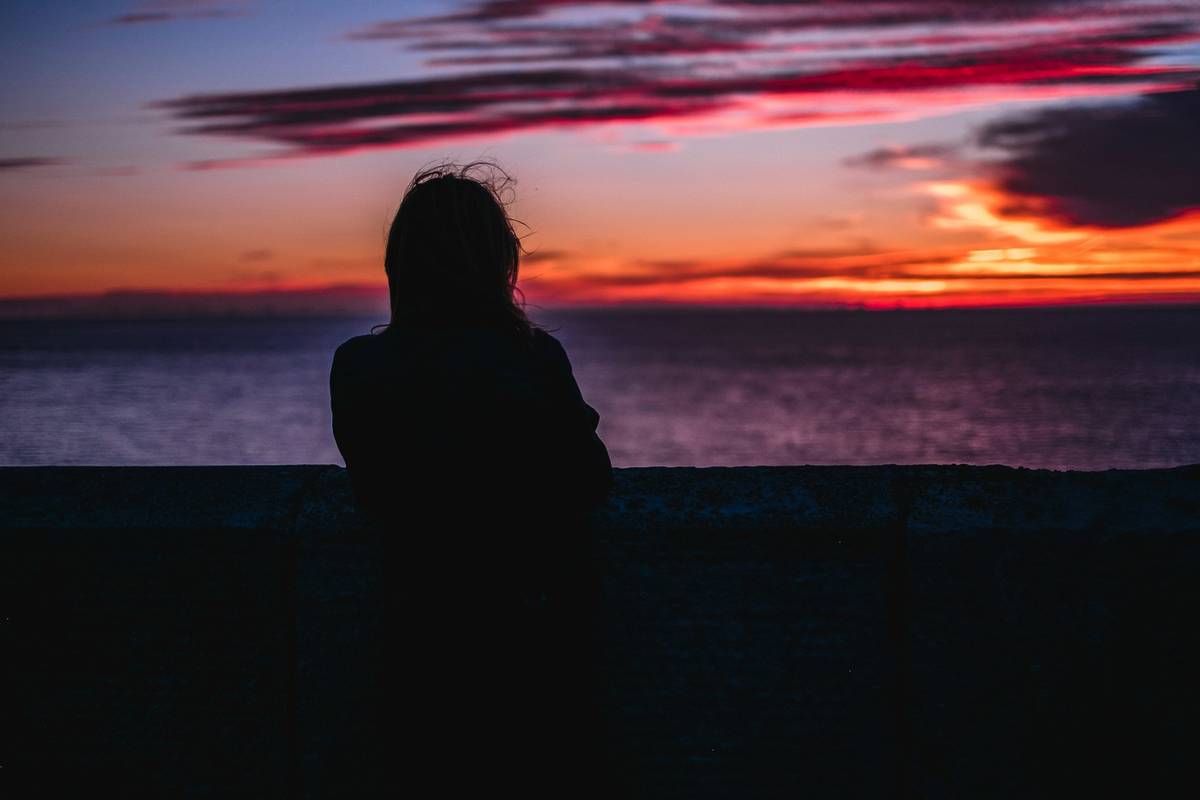 mulher a ver pôr do sol, num estado de saudosismo, curiosidades de portugal