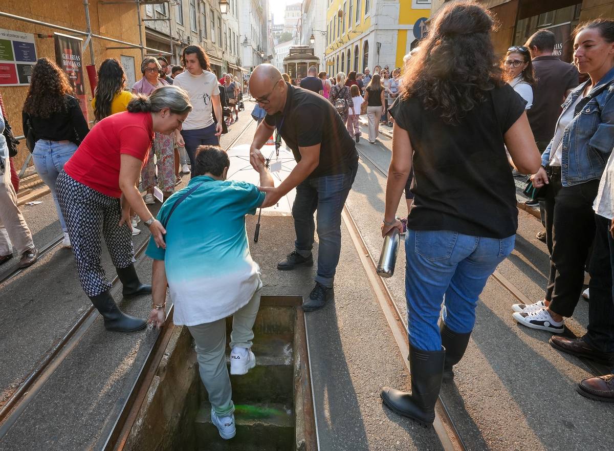 pessoas a descer o alçapão para visitar as Galerias Romanas
