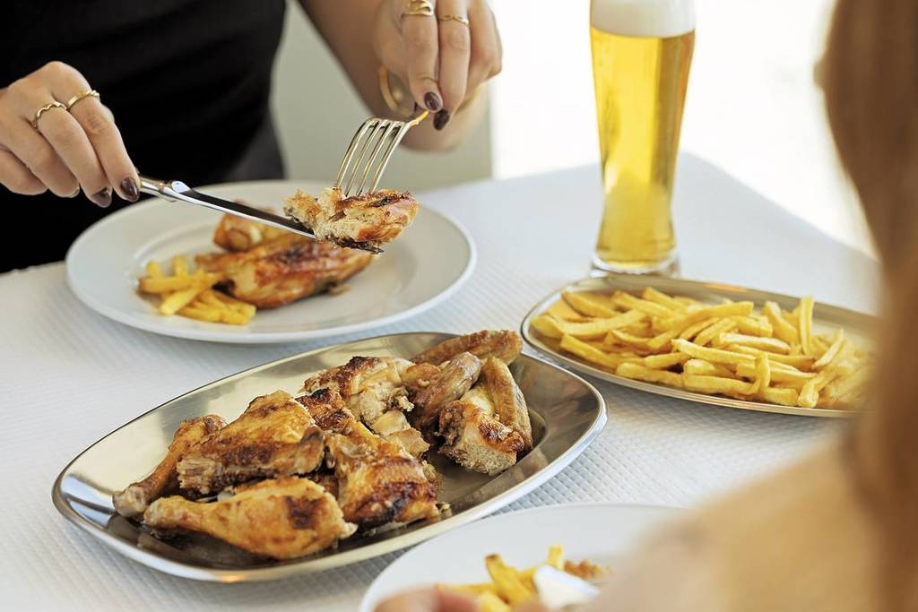 Person eating chicken at Casa do Frango churrascaria in Parque das Nações