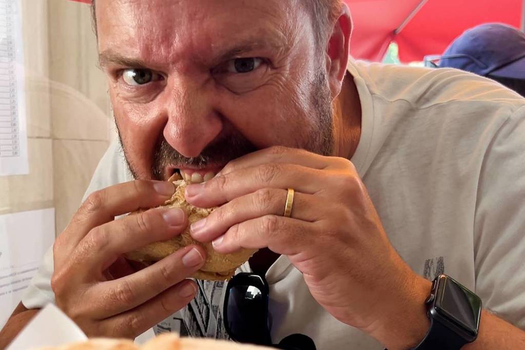 Hombre dando un mordisco a una bifana en la parrilla de Chile.