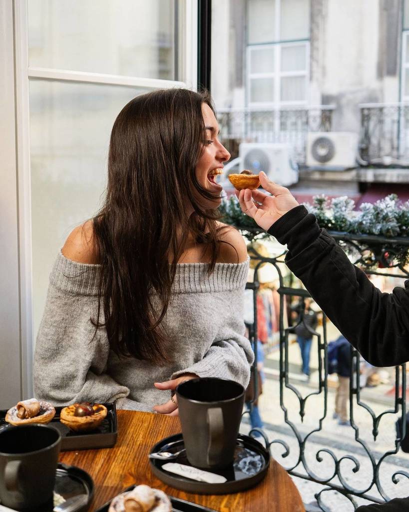 une femme en train de manger un pastel de nata à la pâtisserie nat'elier