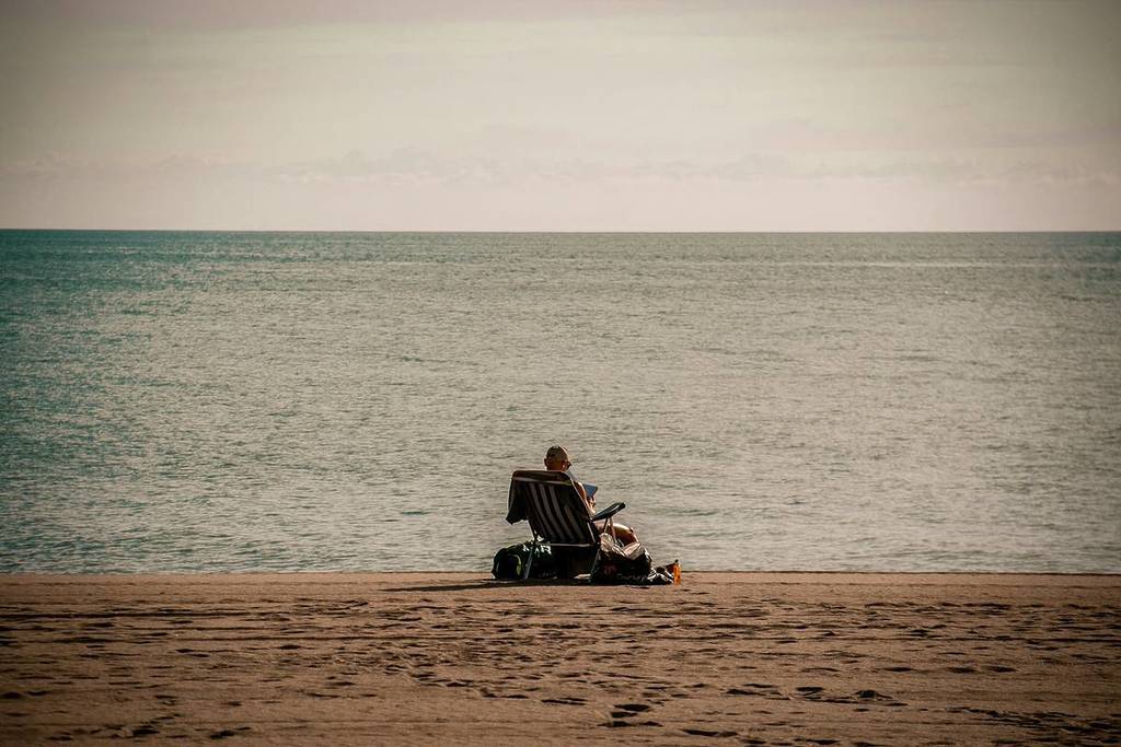 Strand mit Rentner auf einem Stuhl